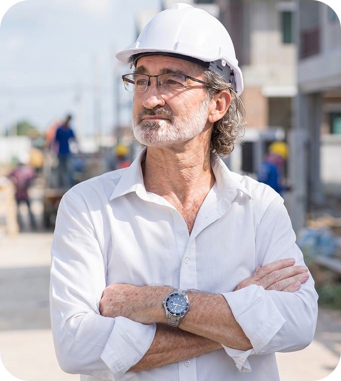 Worker in hard hat, arms crossed, construction site backdrop